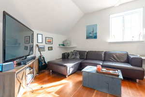 Cottage living area featuring light wood-style floors and lofted ceiling