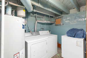 Laundry area with water heater, concrete flooring, and separate washer and dryer