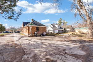 Rear view of main house featuring a chimney, a residential view, brick siding, and concrete driveway