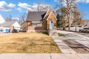 Tudor home with a chimney, brick siding, and roof with shingles