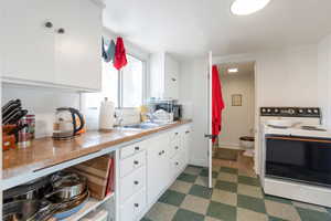 Cottage kitchen with white electric range, white cabinets, light countertops, and stainless steel microwave