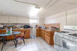 Kitchen featuring white gas range oven, light countertops, wood finish cabinets, and black microwave