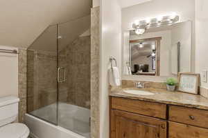 ADU Bathroom featuring lofted ceiling, bath / shower combo with glass door, and vanity