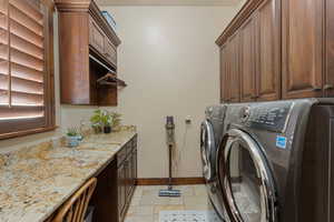Laundry room featuring stone tile flooring, cabinet space, and separate washer and dryer