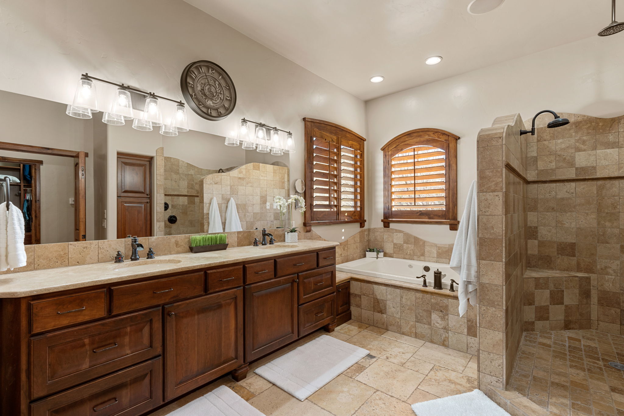 Primary Owner Suite Bathroom with double vanity, a walk in shower, a garden tub, and stone tile flooring