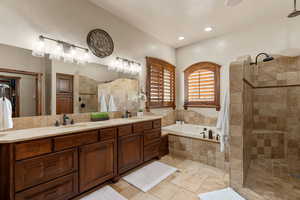 Primary Owner Suite Bathroom with double vanity, a walk in shower, a garden tub, and stone tile flooring