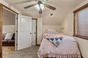 Carpeted bedroom with vaulted ceiling and ceiling fan