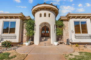 Doorway to property with stucco siding, stone siding, and a tile roof