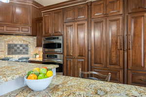 Kitchen featuring light stone counters, stainless steel double oven, and HIDDEN PANTRY