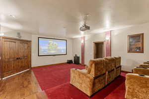 Cinema room featuring wood-type flooring and baseboards