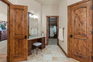 Bathroom with vanity, stone tile flooring, and a walk in closet