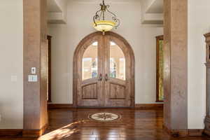 Entryway featuring arched walkways, hardwood / wood-style flooring, french doors, and a high ceiling