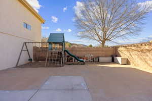 Fenced backyard with a playground and a patio