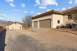 View of home's exterior featuring driveway, stucco siding, a mountain view, and a tiled roof