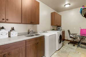 Laundry room featuring stone tile flooring, cabinet space, and washing machine and dryer