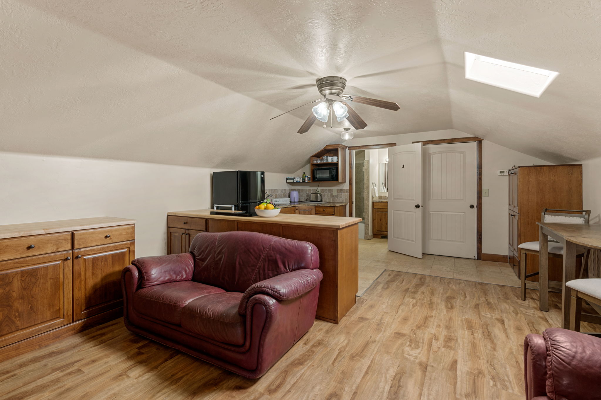 ADU Greatroom w/ light wood finished floors, a ceiling fan, and a skylight