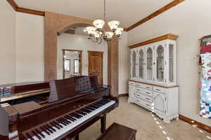 Miscellaneous room featuring ornamental molding, a chandelier, arched walkways, and light colored carpet
