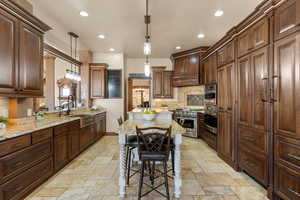 Kitchen featuring light stone counters, pendant lighting, a kitchen breakfast bar, and stainless steel appliances