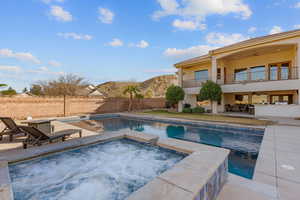 Integrated pool / hot tub with a patio area, a balcony, and a fenced backyard