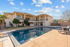 Back of property featuring a patio, a balcony, stucco siding, and a playground