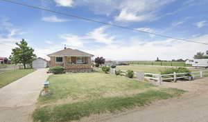 View of front facade featuring an outdoor structure, brick siding, a detached garage, and a rural view