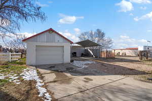 View of front of home featuring driveway, an outdoor structure, a detached garage, and a carport
