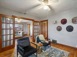 Sitting room with a ceiling fan, wood finished floors, and french doors