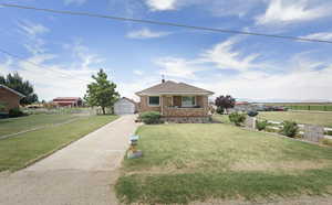 Bungalow-style house featuring brick siding, a garage, an outbuilding, and concrete driveway