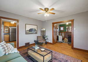 Living area with a ceiling fan, wood finished floors, and a fireplace