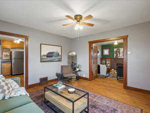 Living room with ceiling fan, wood finished floors, and a fireplace