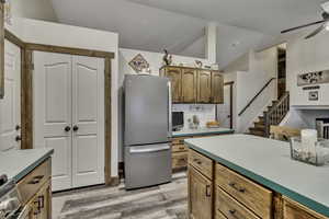 Kitchen with stainless steel appliances, light countertops, ceiling fan, light wood-type flooring, and wood finish cabinetry
