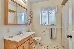 Full bath featuring a shower with curtain, vanity, and light floors