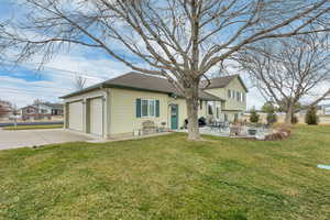 Rear view of property with a yard, roof with shingles, a patio, and driveway