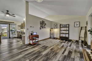 Sitting room with dark wood-type flooring, lofted ceiling, and ceiling fan
