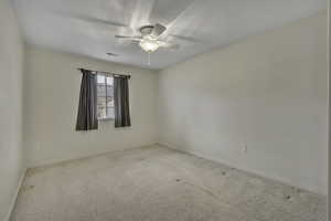 Carpeted spare room with ceiling fan and baseboards