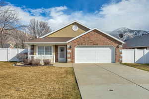Single story home featuring an attached garage, concrete driveway, a gate, brick siding, and a shingled roof