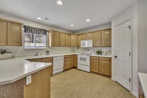 Kitchen with white appliances, light countertops, recessed lighting, light wood finished floors, and light wood finish cabinets