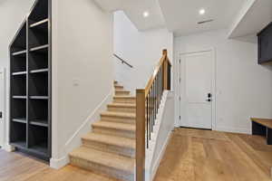 Stairs featuring wood finished floors and recessed lighting