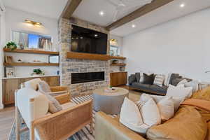 Living room with wood finished floors, a fireplace, and beamed ceiling