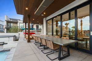 View of patio with outdoor dining space, an outdoor pool, and a hot tub