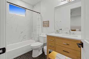 Bathroom with vanity, shower / bathtub combination with curtain, and dark tile patterned flooring