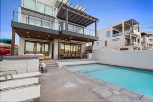 Back of property with stucco siding, a patio, an outdoor bar and dining area, and an outdoor pool