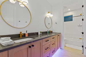 Bathroom featuring double vanity, shower / tub combination, and light tile patterned floors