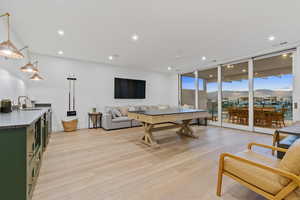 Living area with light wood-type flooring, a ceiling fan, floor to ceiling windows, and recessed lighting