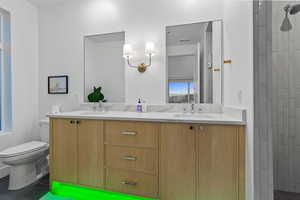 Bathroom featuring double vanity, tiled shower, and dark tile patterned flooring