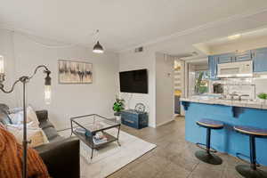 Living area featuring crown molding and light tile patterned flooring