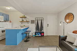 Living area with crown molding and light tile patterned floors