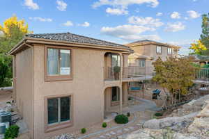 Rear view of house with stucco siding, a patio area, and a balcony