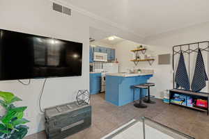 Living area with crown molding and light tile patterned floors