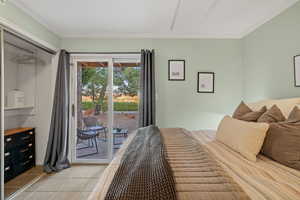 Bedroom featuring light tile patterned floors, ornamental molding, and access to exterior
